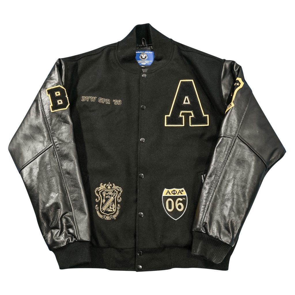 Black wool body letterman jacket with black leather sleeves, gold outlined letter "A" chest patch, custom "DVW SPR '68" embroidery, Alpha Phi Alpha shield patches, and sleeve letter patches from our letterman jackets online collection.